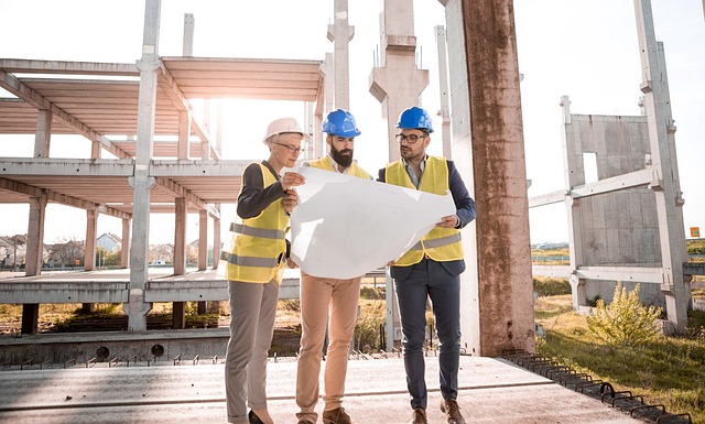 One woman and two men looking at an architecture design while standing on a partially built structure.