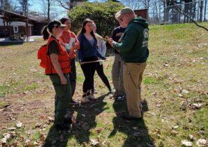 Team members gather around an instructor listening intently as he explains Forestry. Envirothon Training Day 2023.