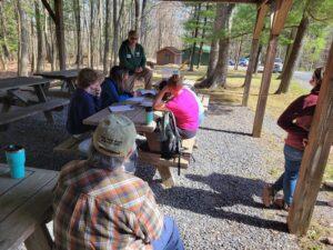 Envirothon students sit at a picnic table listening to a Forestry Board member talk about Forestry. Envirothon Training Day 2023.