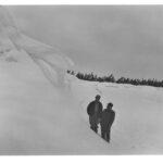 Two men at the bottom of a massive snow drift