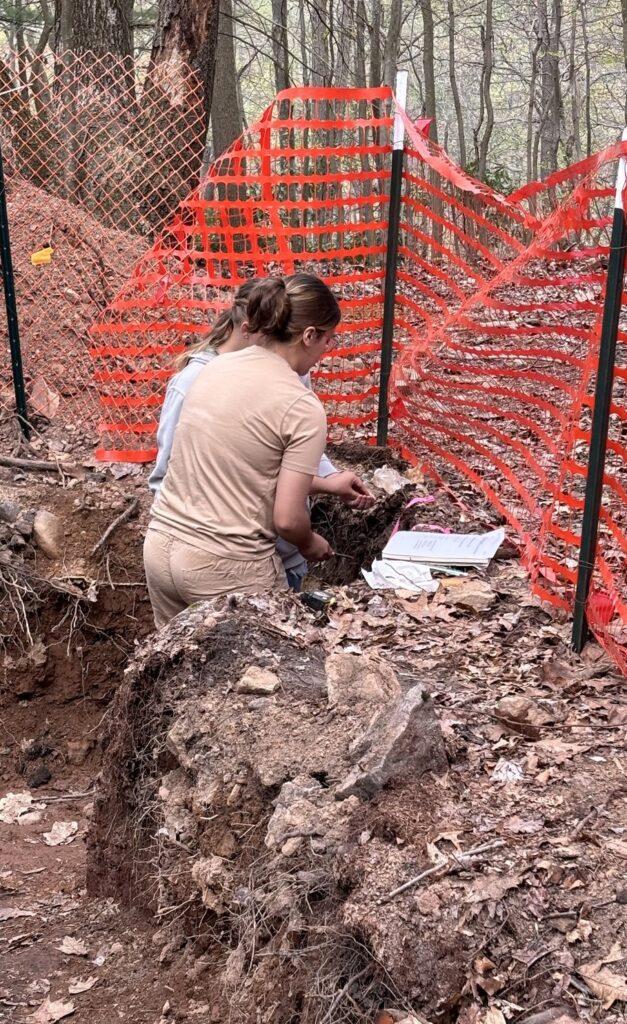 Two female students in a soil pit trying to decipher soil layers