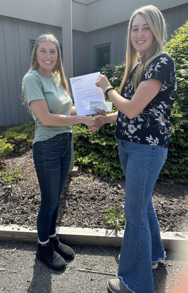 An MDA employee presents the scholarship winner with the check