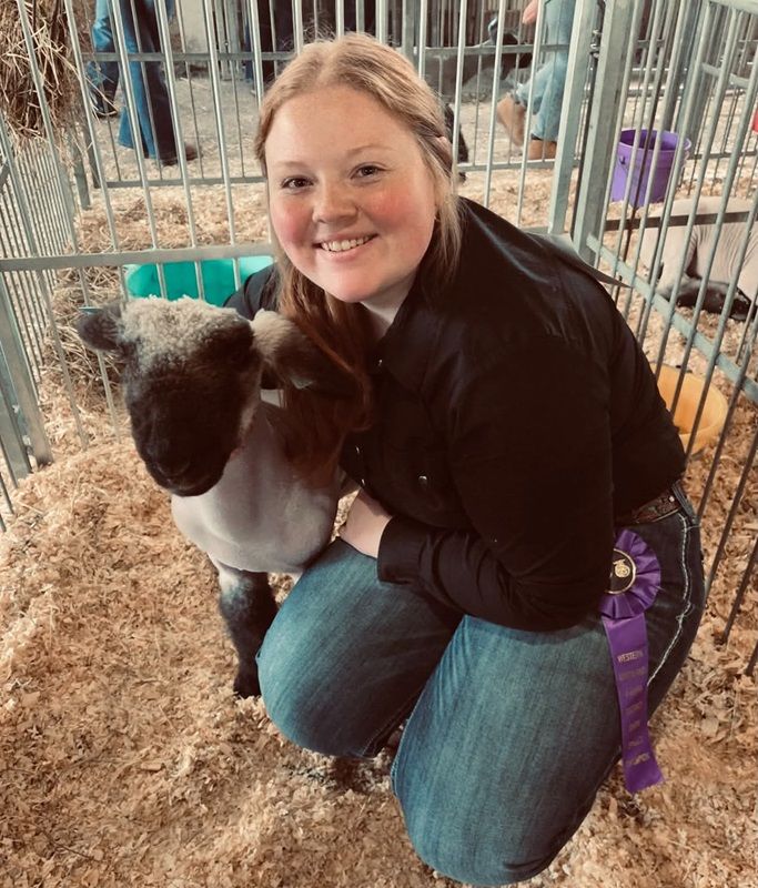 Molly Magruder poses with her Grand Champion Black Lamb