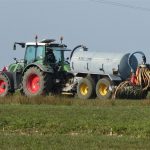 Tractor pulling a manure injector across a field