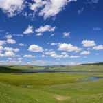 A lush but wet valley under a bright blue sky